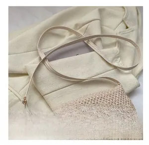 Close-up of cream woven tote bag texture with leather logo label and slim shoulder strap