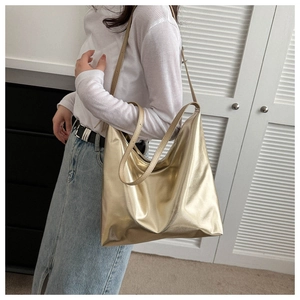 Chic metallic gold tote bag worn by a model in a casual lifestyle setting