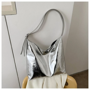 Detail of a large silver metallic hobo shoulder bag with glossy finish and soft folds