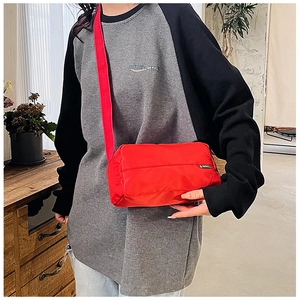 Dettaglio della borsa a tracolla rossa in nylon con ampia tracolla regolabile indossata