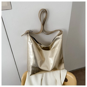 Detailed macro view of the gold metallic textured tote bag with smooth mirror finish surface