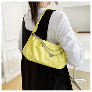 Close-up of bright yellow pleated underarm bag with silver chain and heart charm detail