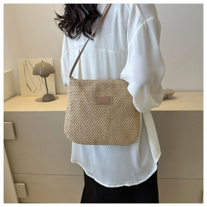 Detail of minimalist straw tote bag featuring square weave texture and brown leather strap