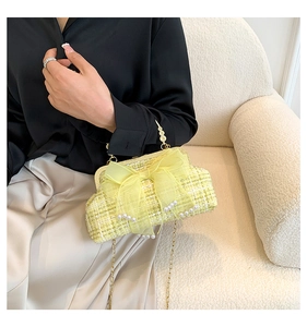Detail of tweed handbag with mesh bow, pearls and gold ornate handle on model