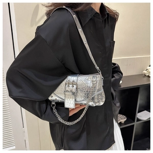 Detailansicht der silbernen Tasche mit Krokoprägung, Metallnieten und einer Zierkette
