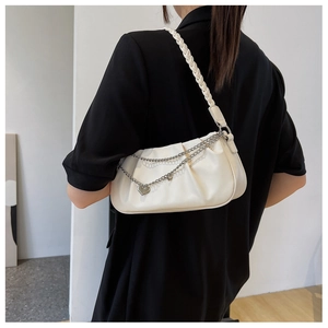 Detail of cream white pleated underarm bag with woven strap and heart chain charm
