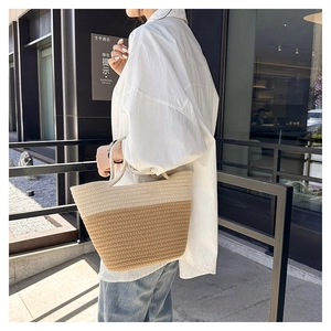 Close-up of woven straw handbag with minimalist bicolor design in a casual street setting