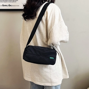 Borsa a tracolla minimalista in nylon nero con etichetta verde indossata da modella