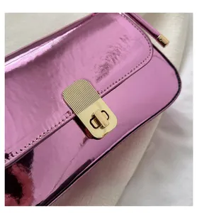 Detail of a bright pink metallic shoulder bag featuring a golden textured twist lock clasp