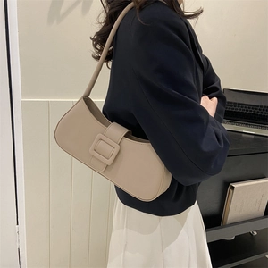 Sac baguette minimaliste beige avec grande boucle carrée présenté par un mannequin