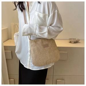 Detail of woven straw crossbody bag with leather patch logo and matching shoulder strap