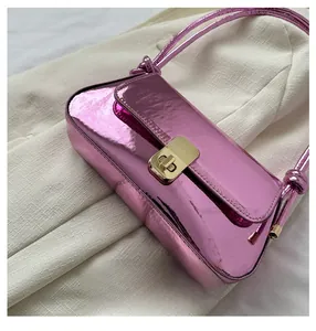 Close-up of pink metallic underarm bag featuring a golden twist lock and knot detail