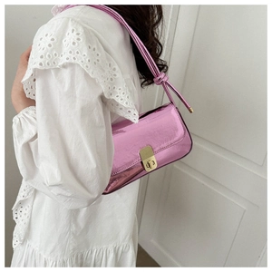 Detail of pink metallic underarm bag featuring a golden twist lock and a stylish knot strap