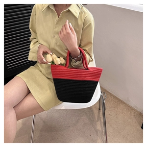 Detailed close-up of a hand-woven bucket bag featuring red and black color block textures