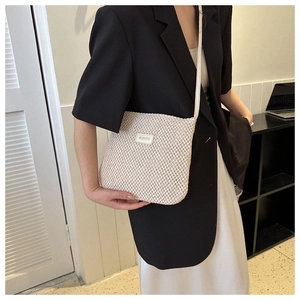 Detail of cream woven tote bag with DIS.HUIBAG metal logo and slim shoulder strap