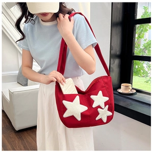 Macro view of the red canvas tote bag showing the white star embroidery and front pocket