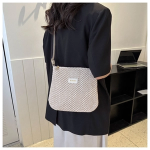 Detail of beige woven tote bag with leather patch logo and delicate mesh texture