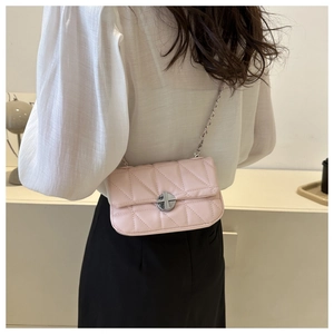 Close-up of pink quilted crossbody bag with silver chain strap worn by a model