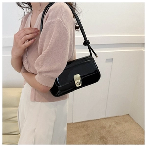 Detail view of black patent leather underarm bag with gold metal clasp on shoulder