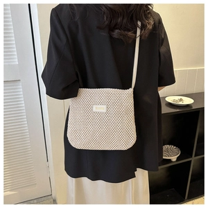 Model wearing a minimalist cream knitted crossbody tote bag with a fine woven texture