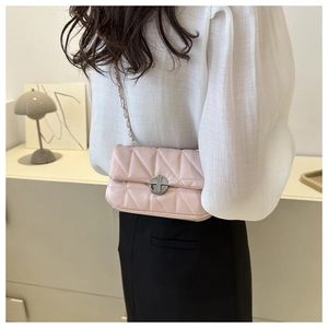Detail showing pink quilted square bag with silver metal lock and chain strap