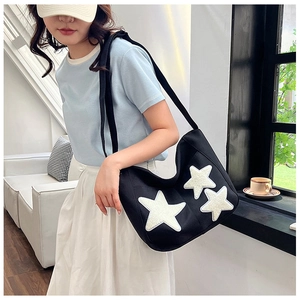 Detailed close-up of a black canvas tote bag featuring three white plush star patches