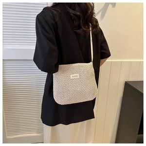 Detail of minimalist woven crossbody bag in cream white showing texture and branded label