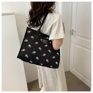 Detail of black jacquard tote bag featuring white rose patterns and fashion instinct label