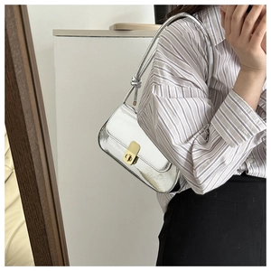 Detail of silver mirror shoulder bag featuring a gold twist lock and metallic texture