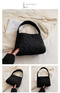 Detail einer schwarzen Stepptasche mit gepolsterten Herzmustern und weicher Textur