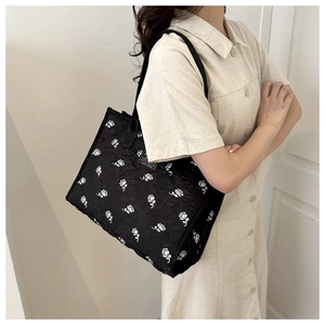 Detail of black tote bag featuring 3D rose jacquard texture and rectangle label