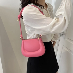 Minimalist pink matte leather crossbody bag with curved design and knot strap detail