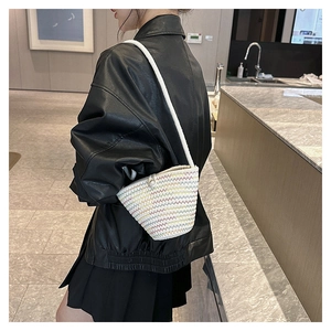 Dettaglio di una borsa a secchiello intrecciata colorata con chiusura a perla e corda