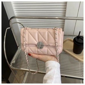 Close-up of pink quilted crossbody bag with silver circular metal twist lock and chain strap