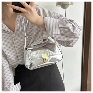 Detail of silver mirror shoulder bag with gold rectangular clasp and knotted strap