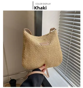 Detail showing the khaki woven straw texture and branded logo plate of this chic tote bag