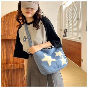 Blue canvas tote bag with cream star patches shown in a casual lifestyle setting
