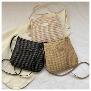Close-up of three woven crossbody bags in black, beige, and khaki with leather brand labels