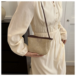 Detail of hand-woven straw crossbody bag with dark brown leather trim and shoulder strap