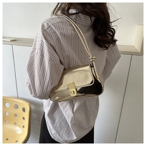 Detail of golden mirror finish crossbody bag with metallic twist lock and knotted strap