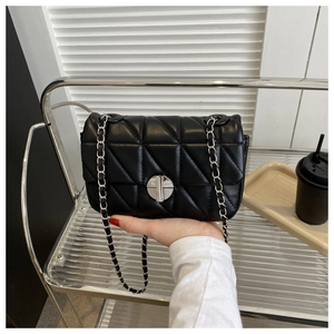 Detail of black quilted leather shoulder bag with silver chain strap and metal lock