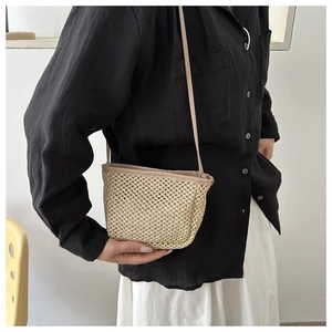 Detail of hand-woven straw crossbody bag showing natural texture and bi-color strap
