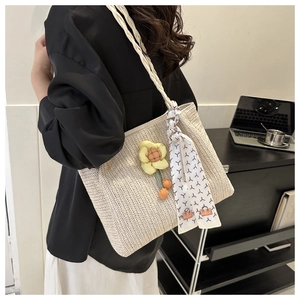 Detail of minimalist beige woven tote bag with floral charm and silk scarf handle decor