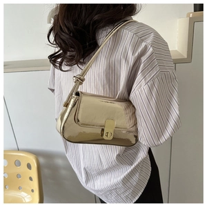 Detail view of the metallic gold shoulder bag with a rectangular twist lock and knotted strap