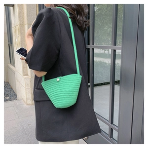 Vista dettagliata della borsa a secchiello verde brillante con chiusura a perla bianca
