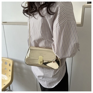 Detail of a metallic gold underarm bag with a glossy finish and premium metal buckle closure