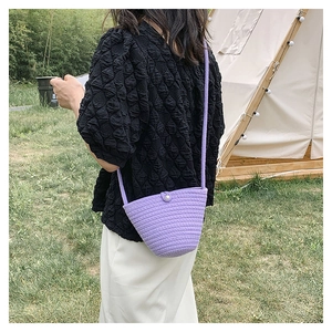 Dettaglio della borsa a secchiello viola intrecciata con bottone di perla e tracolla