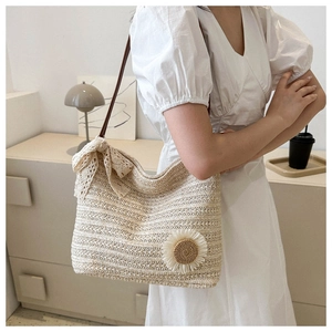 Détail d'un sac cabas en paille tressée avec une fleur de tournesol et un nœud en dentelle