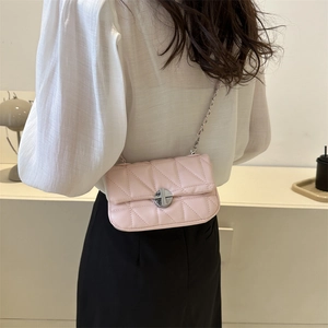 Pink quilted crossbody bag with silver chain strap shown on model in minimalist setting