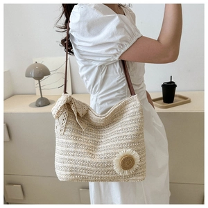 Détail du sac cabas en paille tissée avec fleur de tournesol et bandoulière en cuir